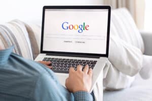 A person holding a computer showing Google homepage. What we search says alot about us.