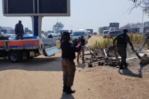 Metro police officers remove structures and belongings during an operation to clear an illegal occupation near Tiger Wheel & Tyre on Winnie Mandela Drive.