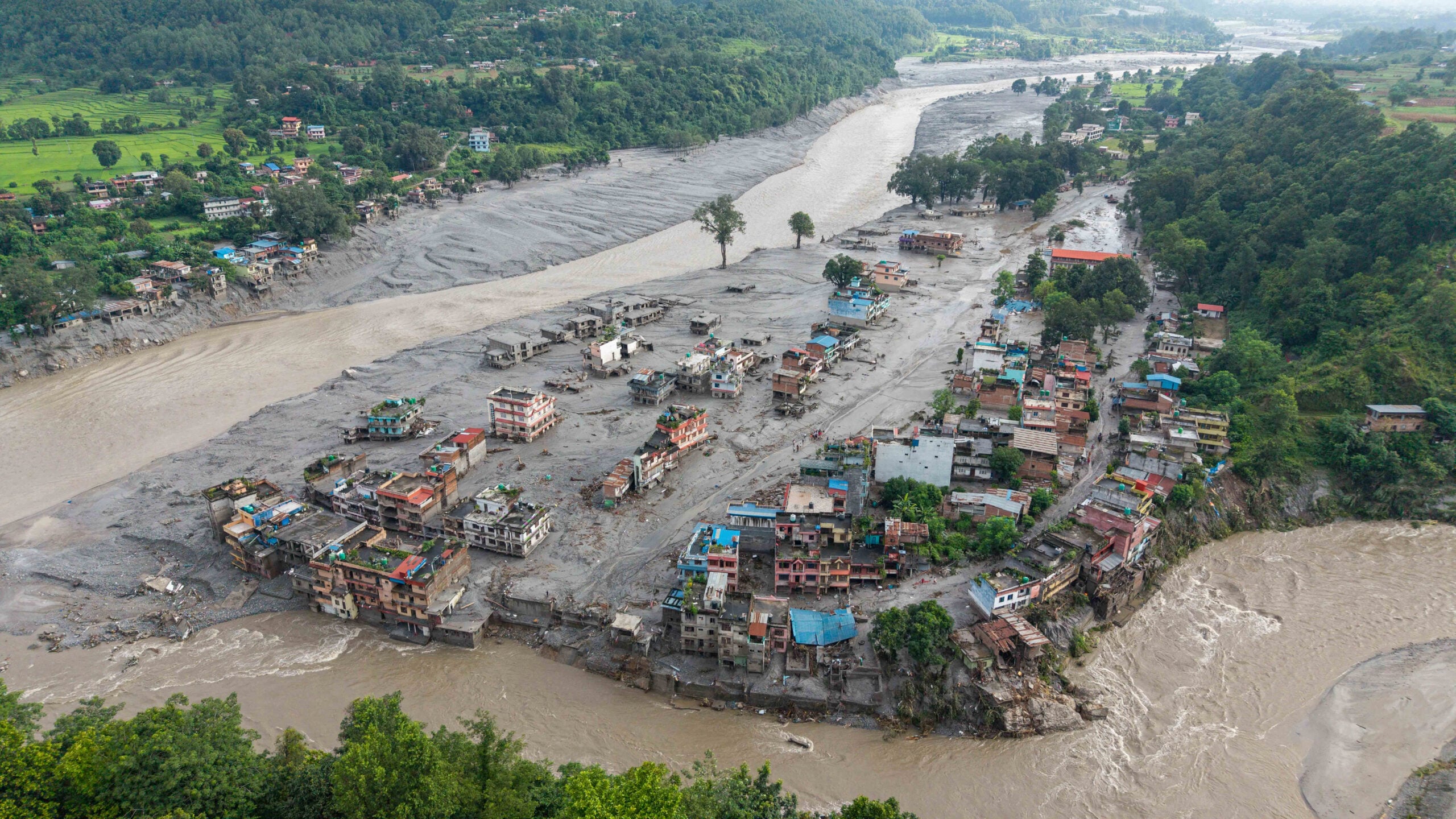 An aerial view shows houses lying deluged in sludge after flash floods at Devighat, Bidur Municipality in Nepal's Nuwakot district on August 27, 2026. Nepal's disaster agency said that 823 people remained out of contact on August 27, more than 24 hours after a deadly flood tore through the border region with Tibet. (Photo by Prabin RANABHAT / AFP)
