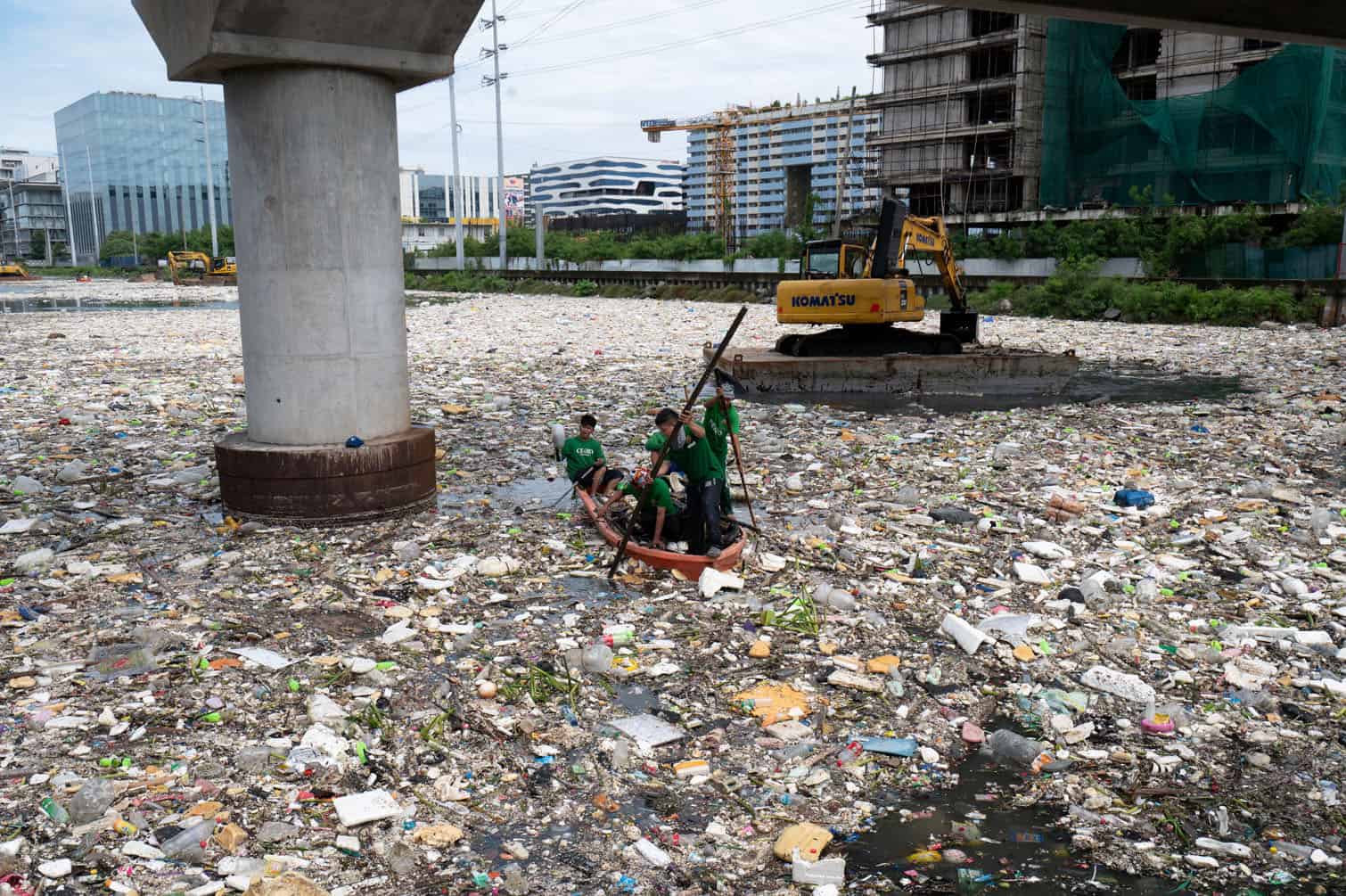 Workers on a plastic boat collect rubbish washed up on a river at the height of heavy rains enhanced by the Southwest monsoon days before, near a shopping complex in Paranaque City, suburban Manila on August 11, 2026. Floods, landslides and accidents driven by a nine-day downpour equivalent to more than a month's worth of rain in some areas have killed at least 16 people in the northern Philippines, rescuers said on August 10. (Photo by Ted ALJIBE / AFP)