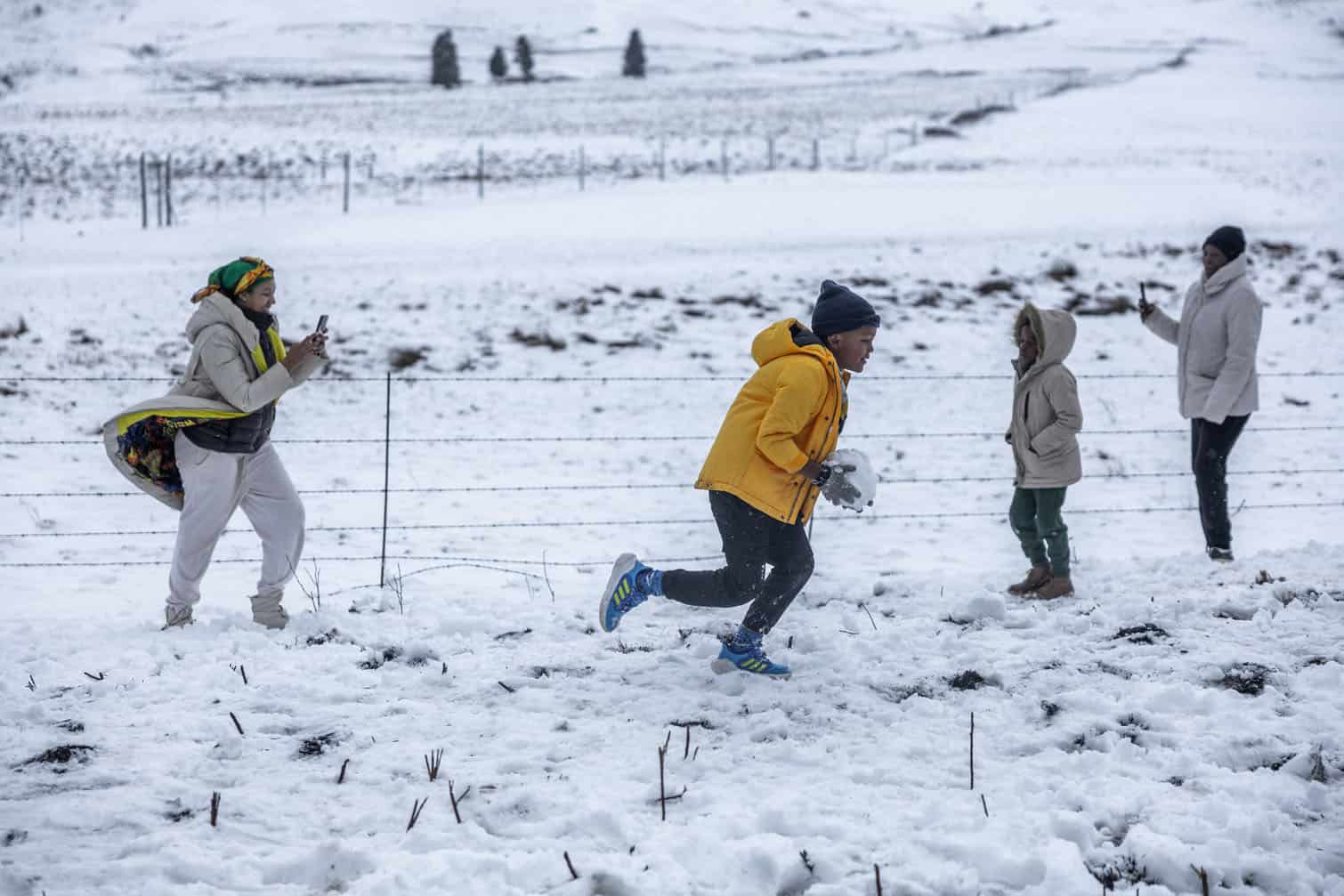 A family gathers to play in snow on Nottingham Road near Pietermaritzburg on August 10, 2026. Parts of the South African province hit with late snow, just ahead of the southern hemisphere spring. (Photo by RAJESH JANTILAL / AFP)