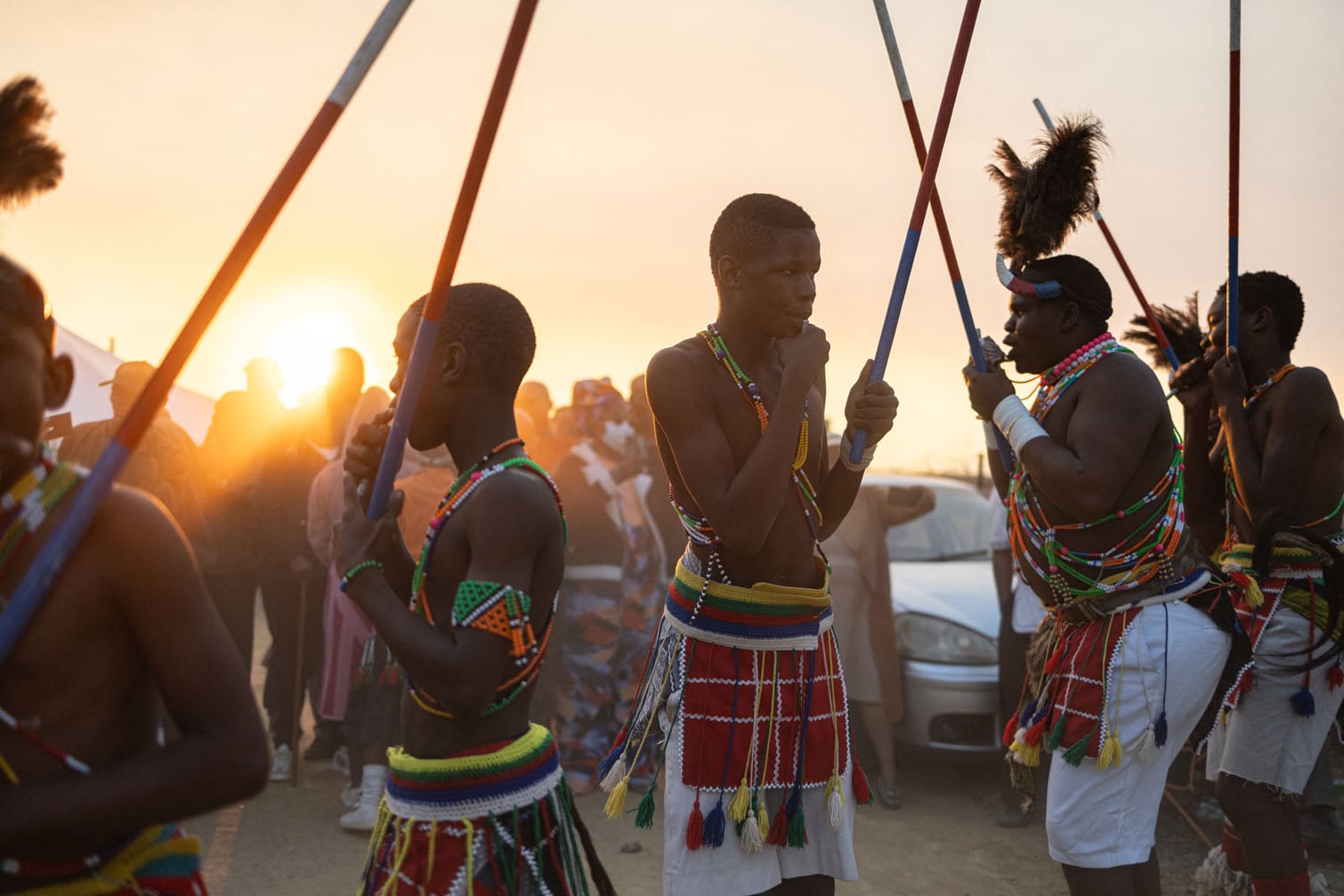 Dancers preform a Bapedi Dinaka dance performance at a family gathering for a lobola (bride price) ceremony in Polokwane, on August 8, 2026. The men, dressed in colourful traditional attire, played dinaka (end blown pipes) for family members and guests. Dinaka is a Bapedi musical and dance tradition in which groups of men play pipes of differing pitches to create a melody, performed at communal and ceremonial gatherings. (Photo by EMMANUEL CROSET / AFP)