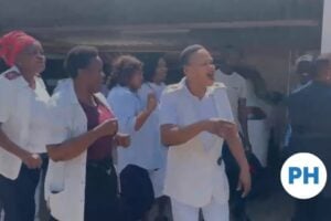 Hospital staff, several in uniform, sing and gesture outside Maphutha Malatji Hospital as they protest over the disputed PMDS ratings.