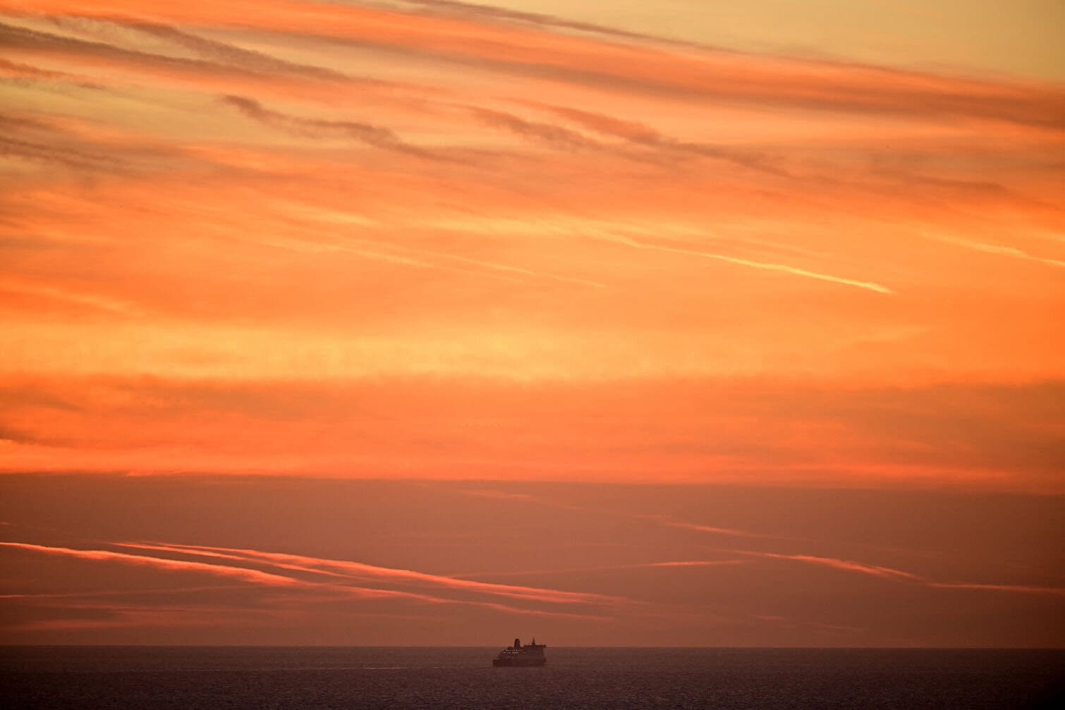 A red sky from the morning sunrise is pictured above a cross-channel Ferry in the English Channel, seen from the Port of Dover in south east England on September 25, 2026. The yearly arrival of tens of thousands of migrants aboard small boats has become highly contentious in Britain, relentlessly seized upon by the hard-right, fuelling growing anti-immigration sentiment, even though data on September 24 showed that 18,565 people had arrived via the route so far this year, down 42 percent year-on-year. (Photo by Ben STANSALL / AFP)