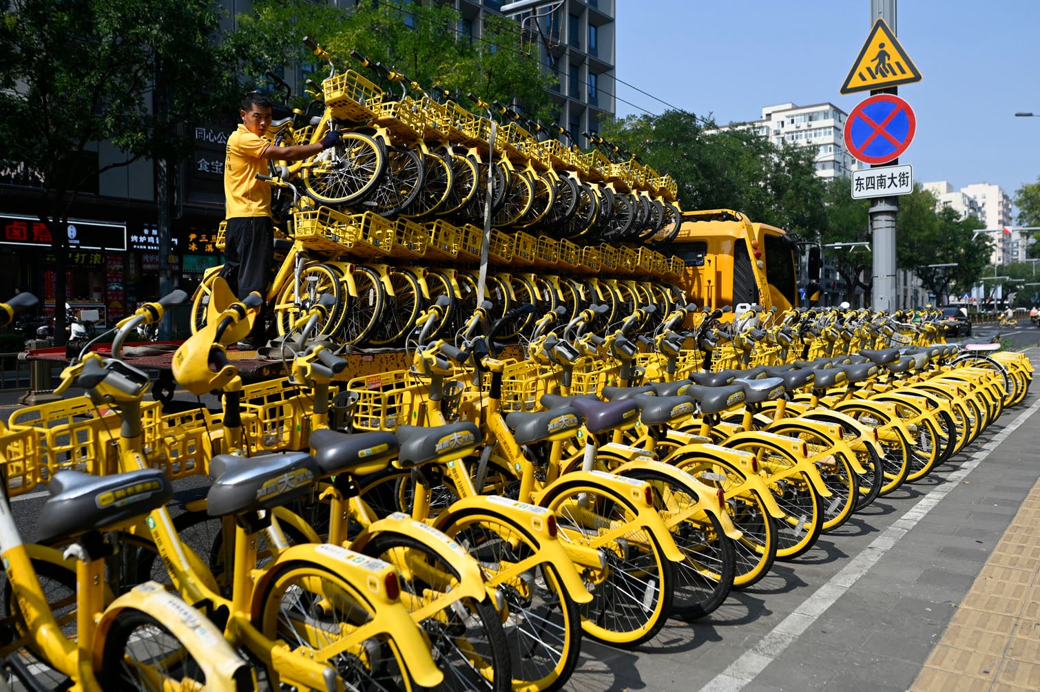 A worker unloads sharing bicycles from a truck along a street in Beijing on September 23, 2026. (Photo by WANG Zhao / AFP)