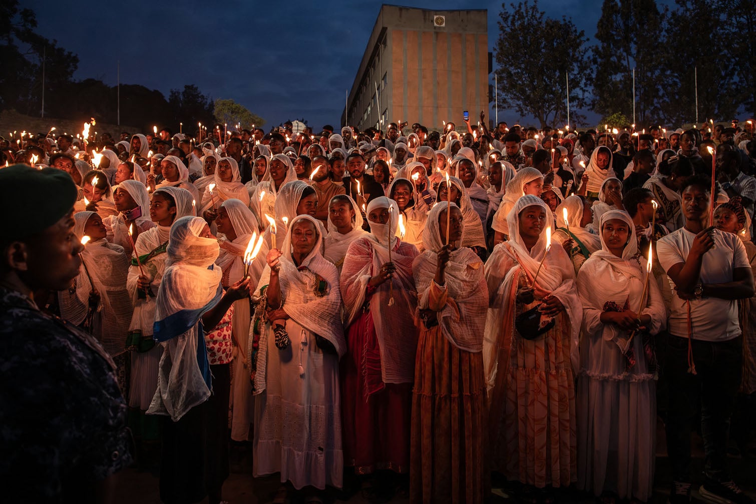 Ethiopian Orthodox believers dressed in traditional white clothing hold lit candles at dusk during Meskel celebrations at Meskel Square in Addis Ababa on September 26, 2026. The Ethiopian Meskel celebration is an annual religious holiday in the Ethiopian Orthodox church that commemorates the discovery of the True Cross in the fourth century by the Roman Empress Helena. (Photo by Solan Kolli / AFP)