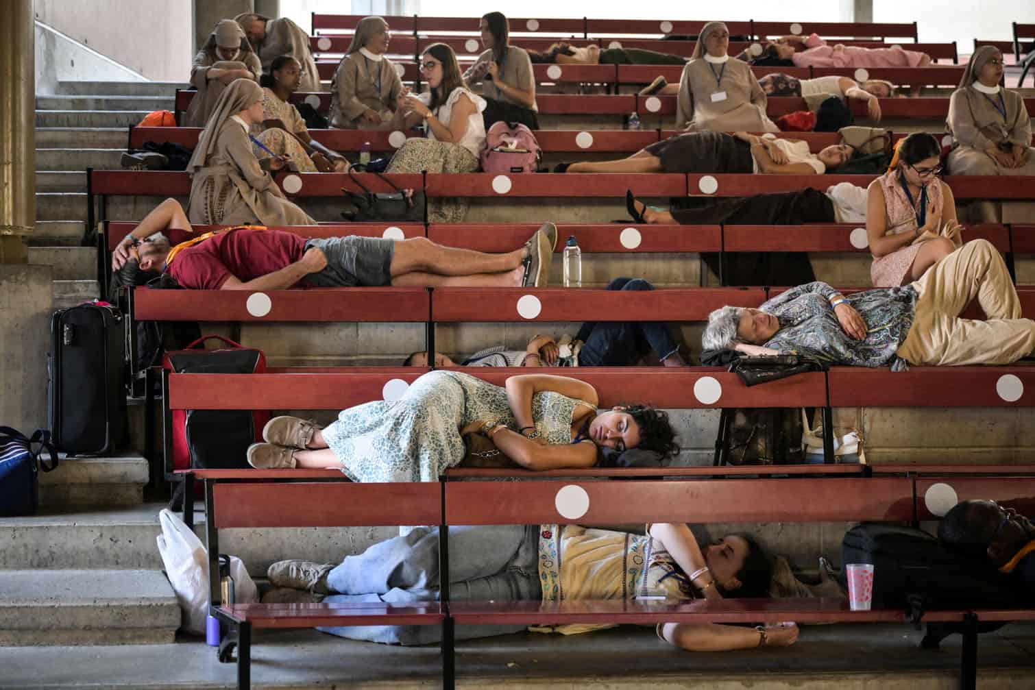 Worshippers and volunteers rest on benches at the Shrine of our Lady of Lourdes, during Pope Leo XIV's visit in Lourdes southwestern France, on September 27, 2026 on the third day of his trip to France. (Photo by Ed JONES / AFP)