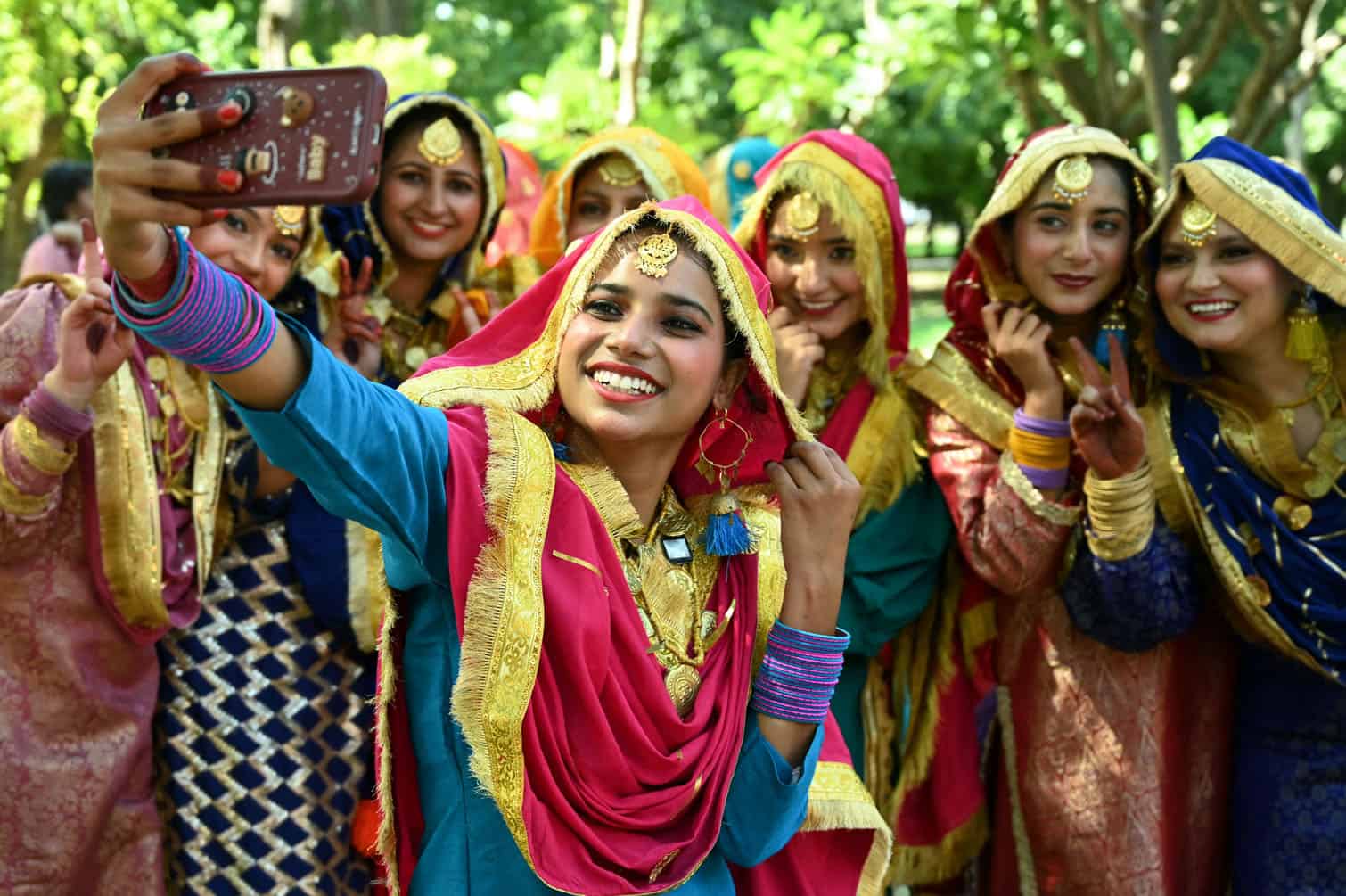 Students in traditional Punjabi dresses take selfies after their performance during the 'Giddha' folk dance competition at a university in Amritsar on September 29, 2026. (Photo by Narinder NANU / AFP)