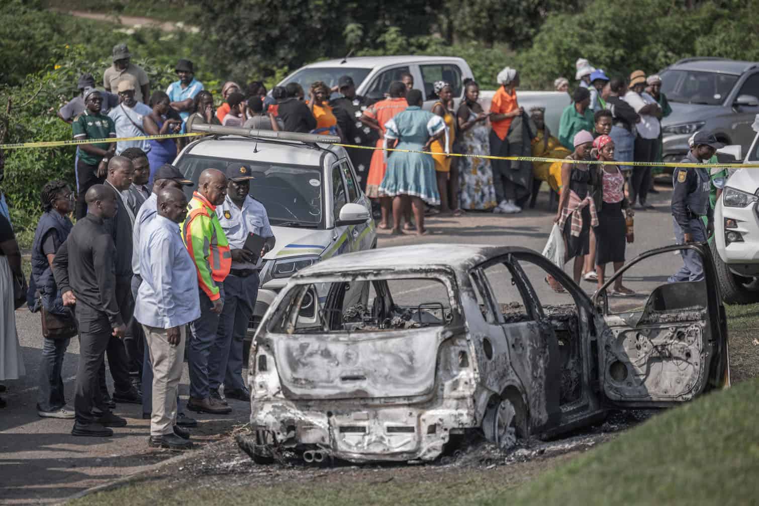The Premier of Kwazulu-Natal province in the colurful jacket is inspects a car belonging to one of the victims was set alight by unknown gunmen at the scene of a mass shooting in the Ziko area of KwaMakhutha, south of Durban, South Africa, September 23, 2026. Armed men stormed a home in the South African city of Durban and killed 11 people, the local government chief said on September 23. “The victims, among them a pregnant woman, were gathered in a house shortly before 11:00 p.m. (6:00 p.m. Brasília time) on September 22 when the armed assailants entered the premises and opened fire,” Thamsanqa Ntuli, head of the provincial government of KwaZulu-Natal, whose main city is Durban, told AFP. (Photo by RAJESH JANTILAL / AFP)
