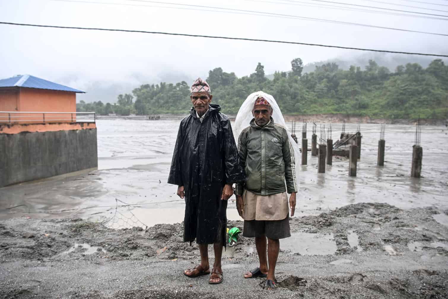 Shree Krishna Nepal (L) and his brother Lok Nath Nepal stand in front of their washed-out house in the aftermath of the August 26 flash floods, at Belkotgadhi in Nepal's Nuwakot district on September 25, 2026. The Himalayan nation suffered one of the worst catastrophes in its history late last month when a tsunami-like flood, triggered by a high-altitude glacial mountain collapse along the Nepal-China border, cut a swathe of destruction. More than 1,400 people died, 6,000 are still missing, and the economic devastation runs in the billions of dollars. (Photo by Prakash MATHEMA / AFP)