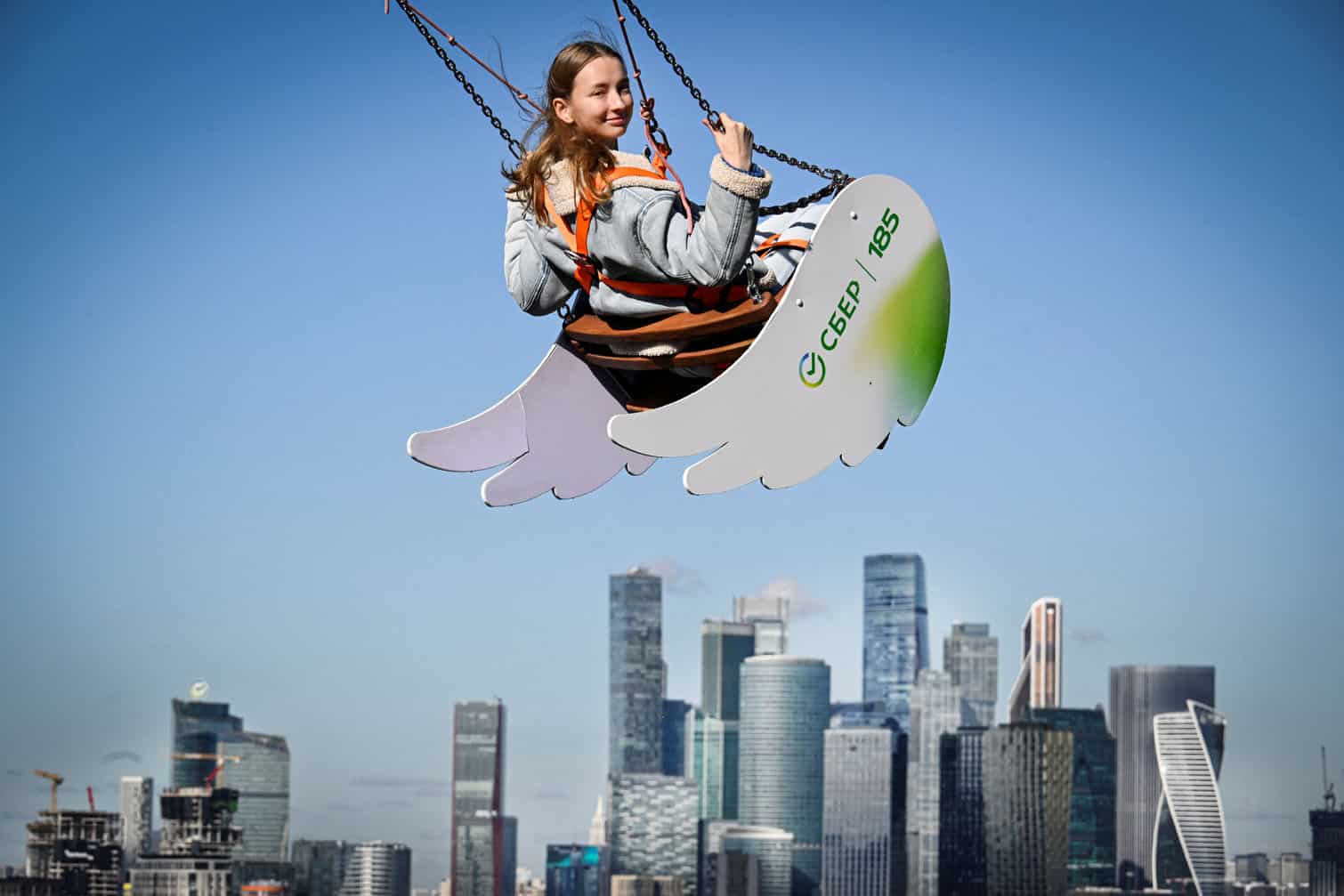 A woman swings at the observation point at Vorobyovy Hills in front of the buildings of the Moscow International Business Centre (Moskva City) in Moscow on September 30, 2026. (Photo by Alexander NEMENOV / AFP)