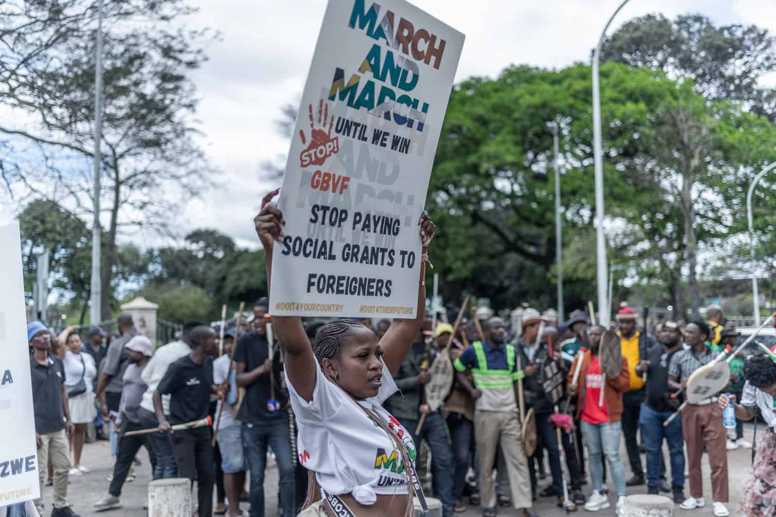 A protestor from anti-illegal immigration group, March and March Movement holds a placard during a "Day of Action" solidarity walk against gender-based violence (GBV) in Durban on September 30, 2026. The march takes place to honour victims of gender-based violence and call for urgent government action amid concern over the recent killings of women in the city of Ekurhuleni and other areas  of South Africa. (Photo by RAJESH JANTILAL / AFP)