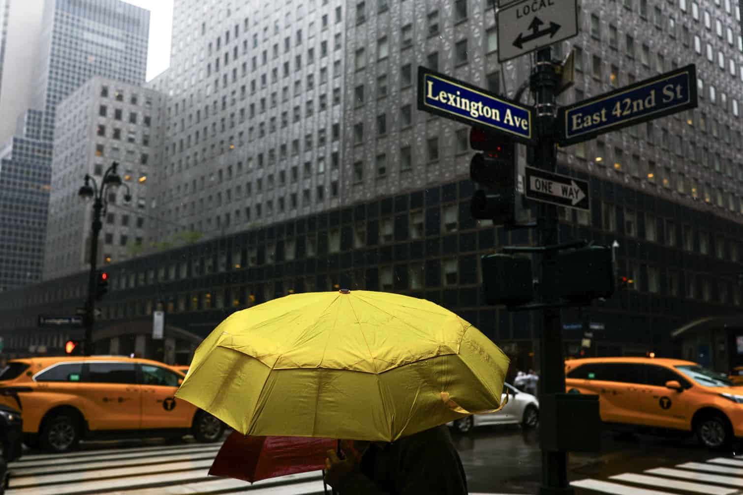 A person walks near Grand Central terminal in the Manhattan borough of New York City on September 27, 2026. A powerful autumnal storm lashed the heavily populated US Northeast corridor with wind, rain and large waves, knocking out power for thousands and killing at least one person. Nor'easters, as storms like these are known, can cause billions of dollars in damage as they bring torrential rain, sometimes snow, strong winds and heavy storm surge flooding to large swaths of the US East Coast. The National Weather Service (NWS) said Sunday morning that the storm was "slowly weakening" after causing days of havoc up and down the East Coast. (Photo by CHARLY TRIBALLEAU / AFP)
