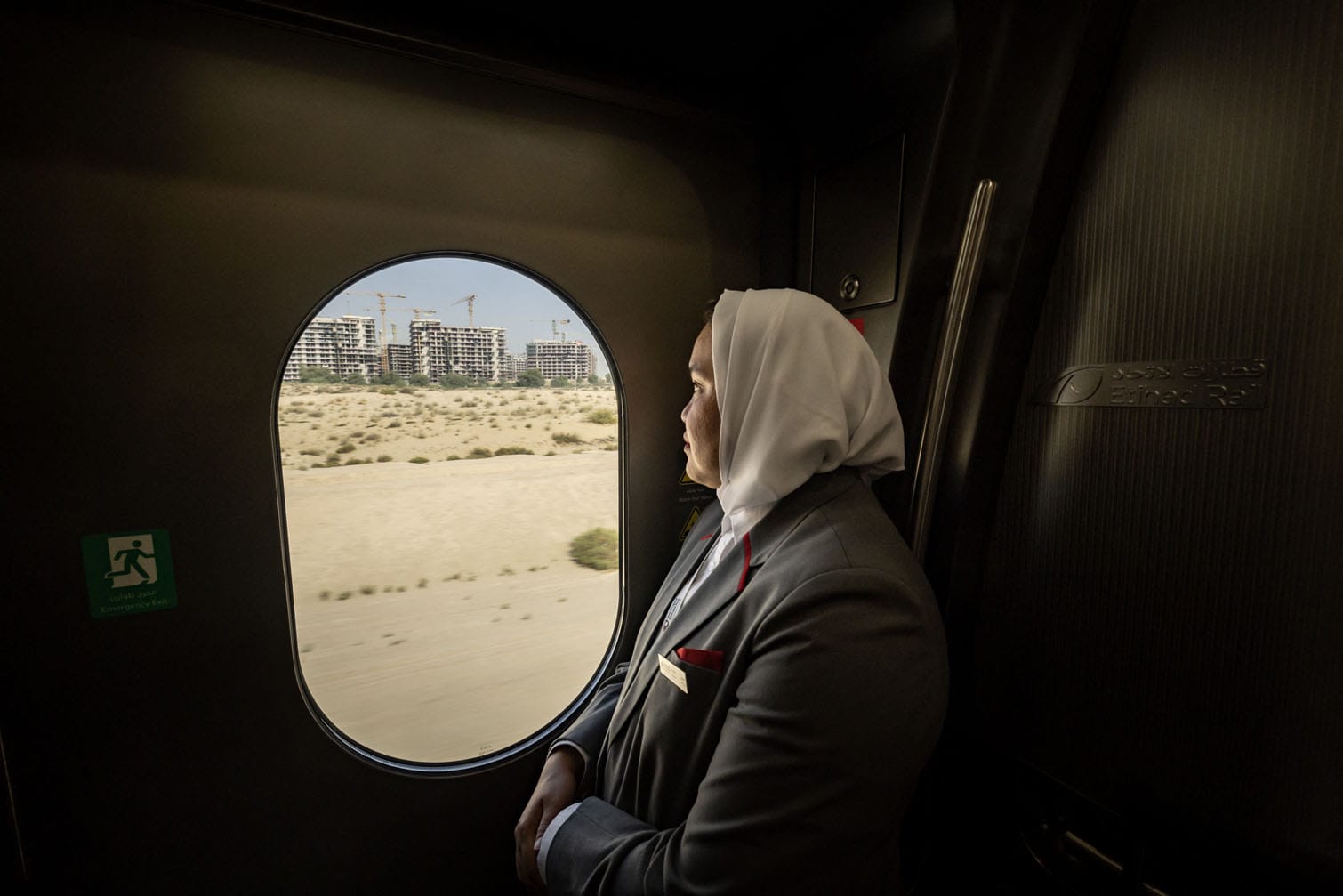 A staff member looks out a window onboard an Etihad Rail train on September 29, 2026, during the inaugural passenger service connecting from Abu Dhabi's Mohamed Bin Zayed City station to Dubai's Yalayis station. (Photo by FADEL SENNA / AFP)