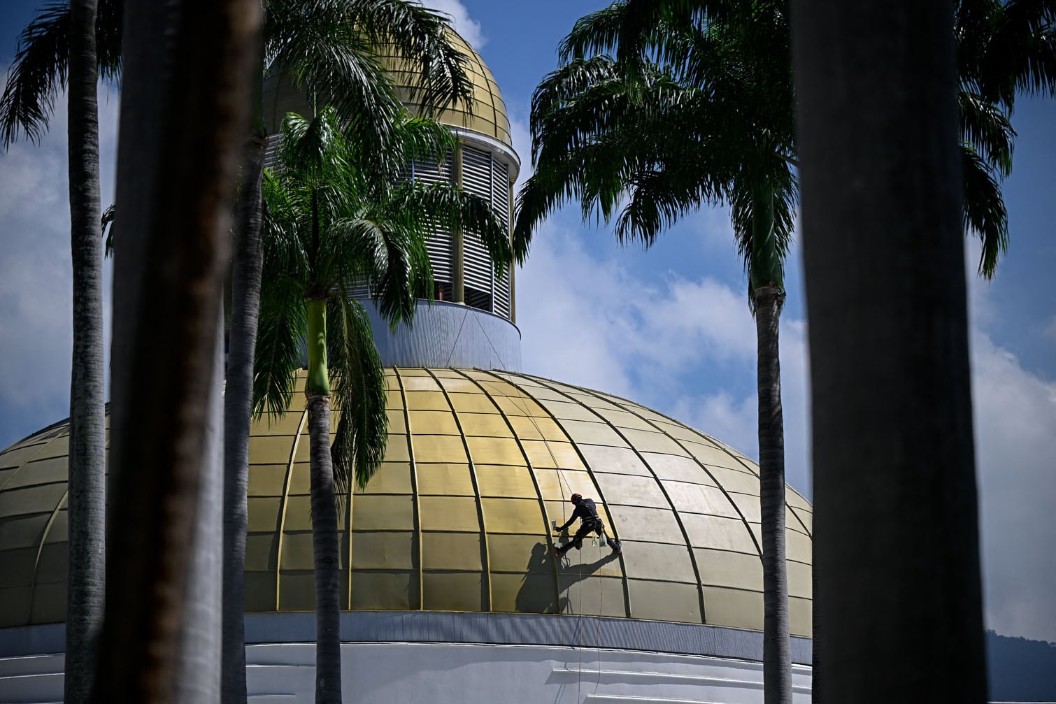 A worker paints the dome of the Federal Legislative Palace ahead of a session of Venezuela's National Assembly in Caracas on September 23, 2026. Venezuela's parliament approved a resolution on September 23 backing acting President Delcy Rodriguez's participation in the United Nations General Assembly (UNGA), amid criticism over her political rapprochement with the United States. (Photo by Federico PARRA / AFP)