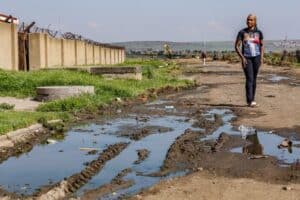 Owethu Rubeka stands in Sulima Street, where sewage collects in the badly deteriorated road near her family’s home and preschool.