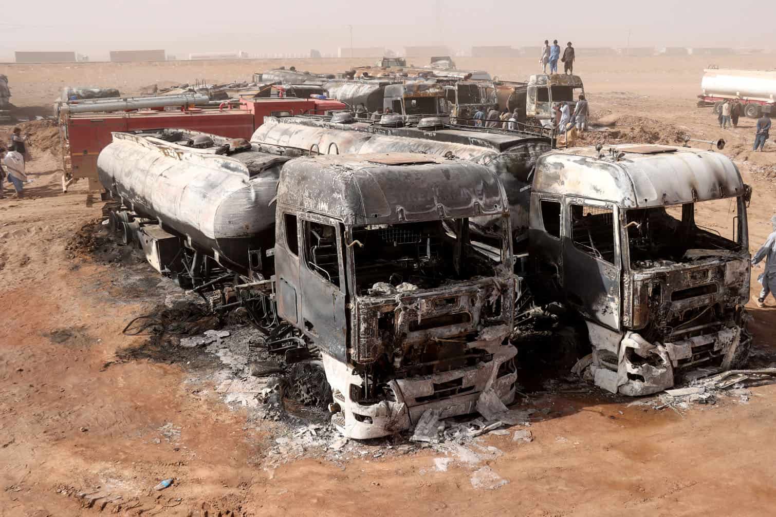 Afghan men stand above the wreckage of fuel tankers following a fire at the Islam Qala border crossing in western Afghanistan's Herat province on October 1, 2026. (Photo by Mohsen KARIMI / AFP)