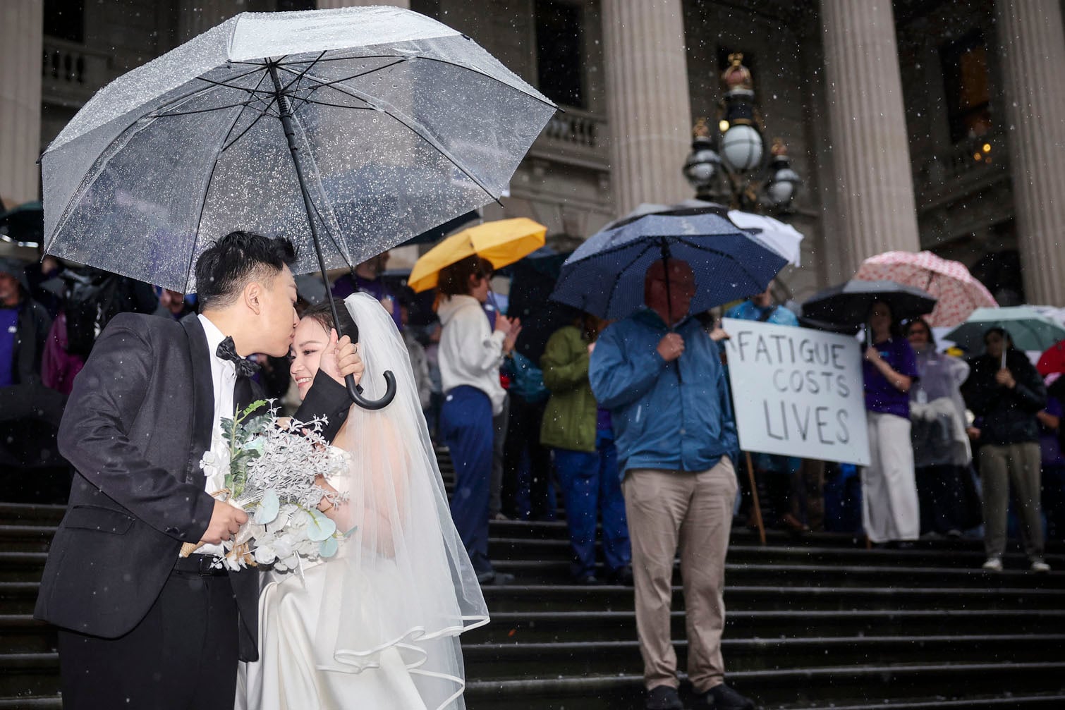 A couple poses for wedding photos as doctors and members of the Victorian branch of the Australian Medical Association (AMA), protest outside Parliament House in Melbourne on October 1, 2026. (Photo by Martin KEEP / AFP)