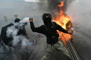 A protester throws back a tear gas canister