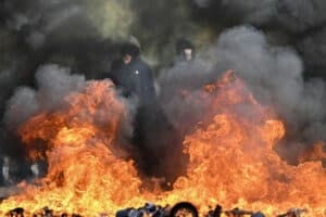 Protesting students stand in front of a burnt barrier
