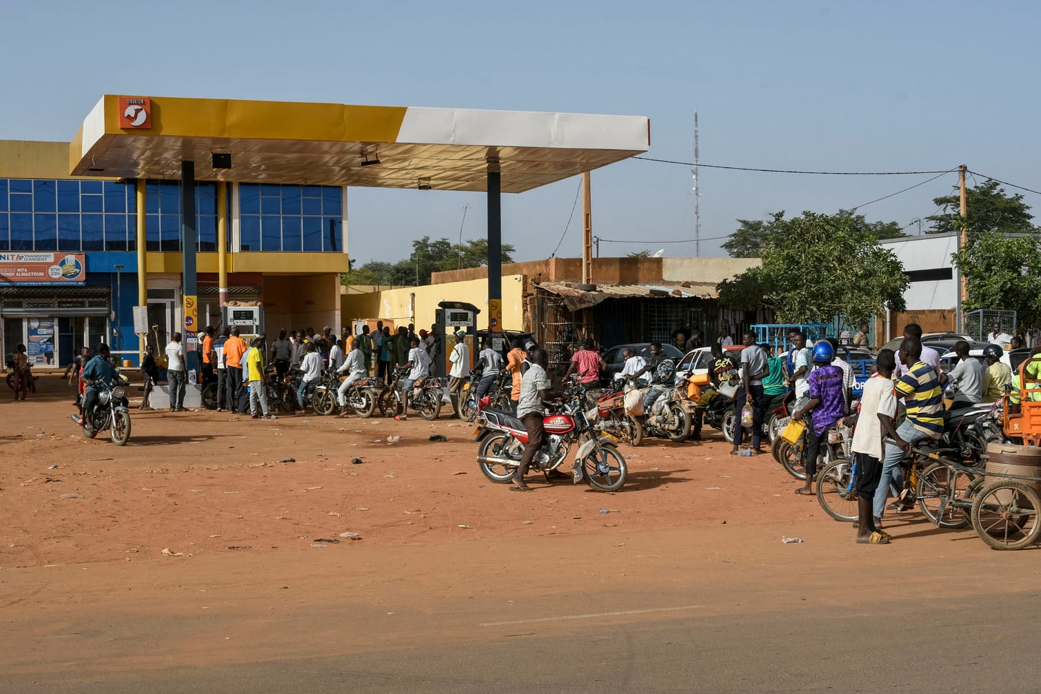 Motorcyclists queue to fill up their motorbikes at a petrol station in Niamey on October 18, 2026. The gasoline shortage affecting several cities in Niger has reached the capital, Niamey, where lines stretched out in front of gas stations on October 18. Since July 2023, Niger has been ruled by a military regime that champions sovereignty, particularly over the country’s mineral resources, including its oil production. (Photo by AFP)