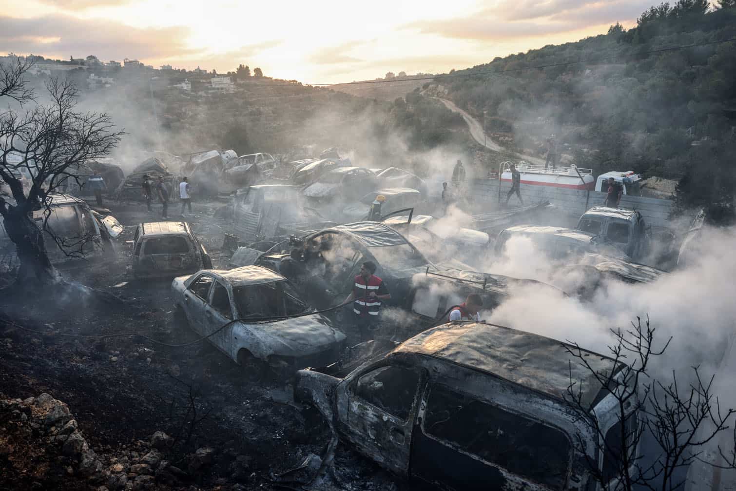 Palestinians inspect burnt cars and olive trees at a scrapyard following an attack allegedly carried out by Israeli settlers in the village of Ayn Yabrud, northeast of Ramallah, in the Israeli-occupied West Bank, on October 4, 2026. Violence has flared in parallel to Israel's offensive in Gaza in response to the massive Hamas attack of October 7, 2023. Israeli settler attacks against Palestinians including beatings, vandalism and arson averaged six a day in the first half of the year, according to the United Nations, with Israel facing mounting international criticism over the rise in Israeli settler violence. (Photo by Zain JAAFAR / AFP)