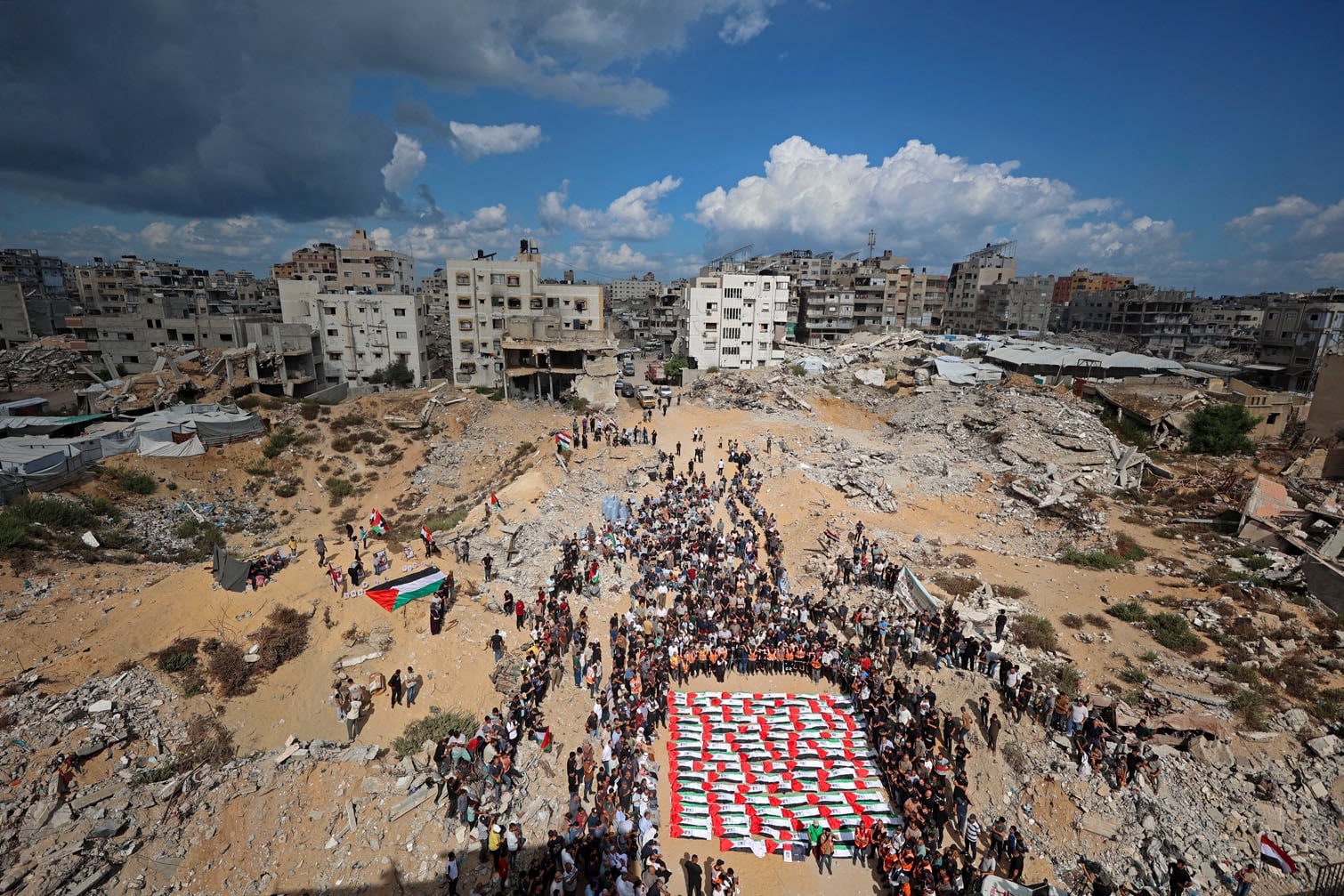Palestinian mourners gather for a mass funeral procession in Gaza's al-Yarmouk neighborhood on October 1, 2026, following the recovery of 105 bodies from beneath the rubble of the al-Taj residential block which was destroyed by Israeli strikes. (Photo by Omar AL-QATTAA / AFP)